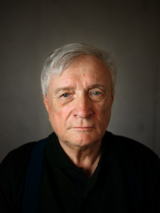 Wystawa Stanisława Wieczoreka, Galeria Test, 2013 rok. Zdjęcie portretowe. Twarz starszego mężczyzny w czarnej bluzce. Tło szare, cieniowane. 